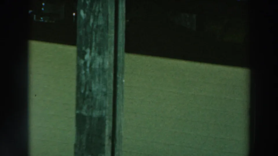 1964 Lake Winnebago frame with a weathered wooden post in the foreground and pale green water or structure behind it during the pan.