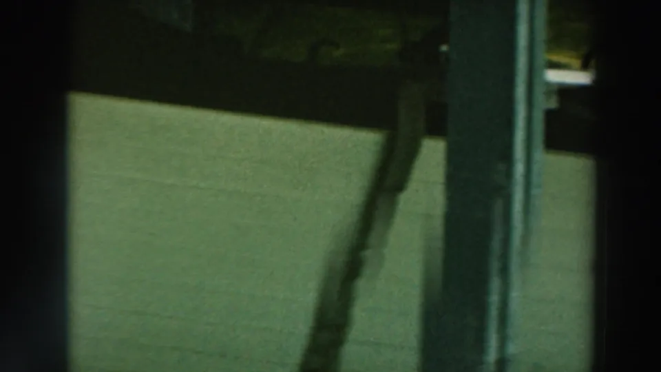 1964 Lake Winnebago 8mm frame showing a white boat hull stored beneath a wooden pier, partly obscured by vertical posts.