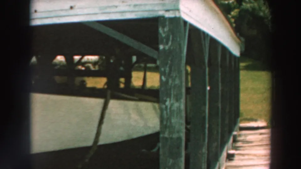A closer angle shows weathered wooden posts, dock boards, and the white boat tucked below the pier.