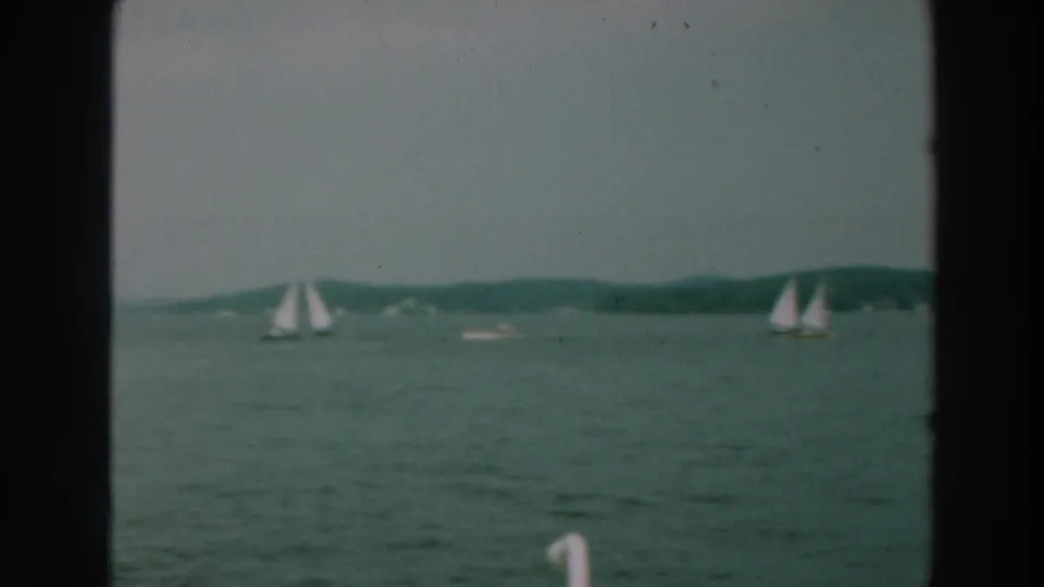 Wide 8mm view of Lake Winnebago in 1964 showing two distant sailboats, calm horizon, and green-blue water.