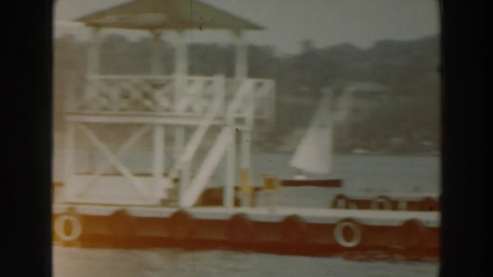 Lake Winnebago dock scene with a covered wooden platform, tire bumpers, water, and small sailboats in the background.