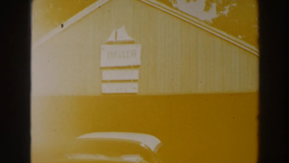 A wooden lakeside building with a BIEGLER sign appears behind the roofline of a parked car.