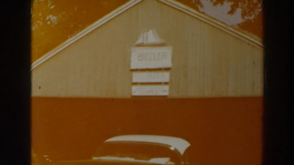 The BIEGLER sign is visible on a wooden gabled building, with a mid-century car parked in the foreground.
