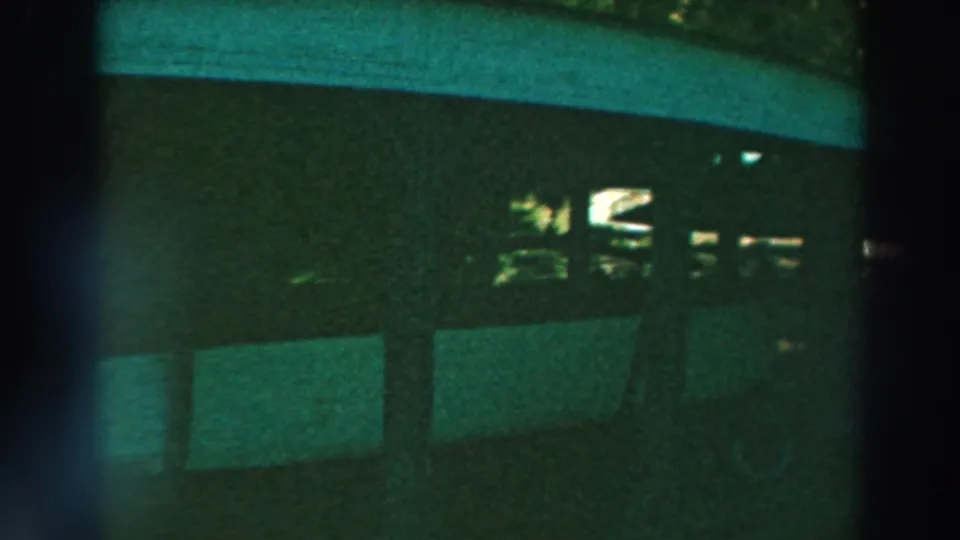 1964 Lake Winnebago night frame with stall-like partitions, dark foreground framing, and small bright areas inside the structure.