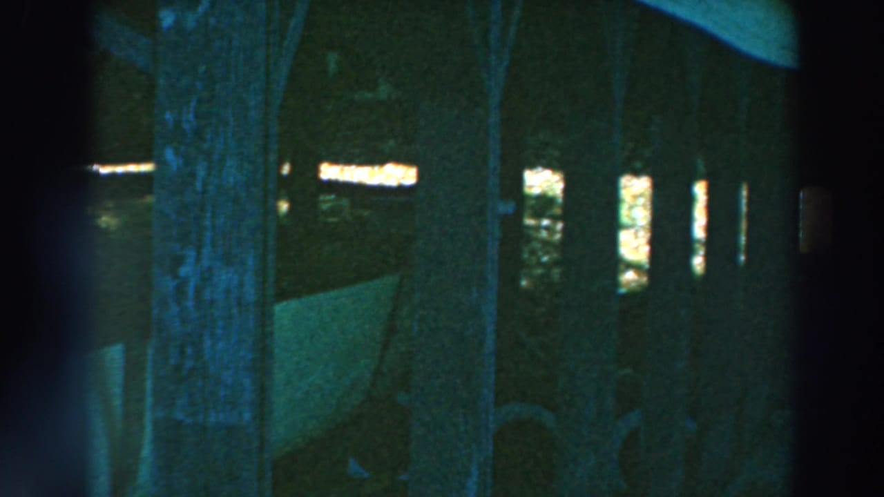 Low-light 8mm view beneath the Lake Winnebago pier, with vertical posts and the white stored boat crossing the frame.