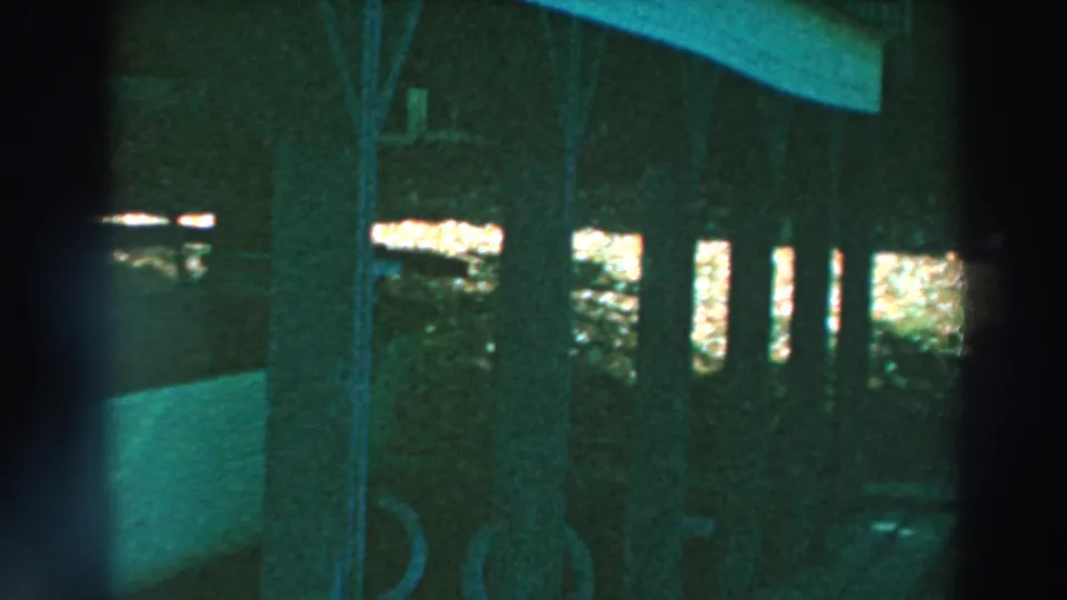 Final frame of the dim Lake Winnebago pier view, with posts, diagonal framing, and the stored white boat still visible.