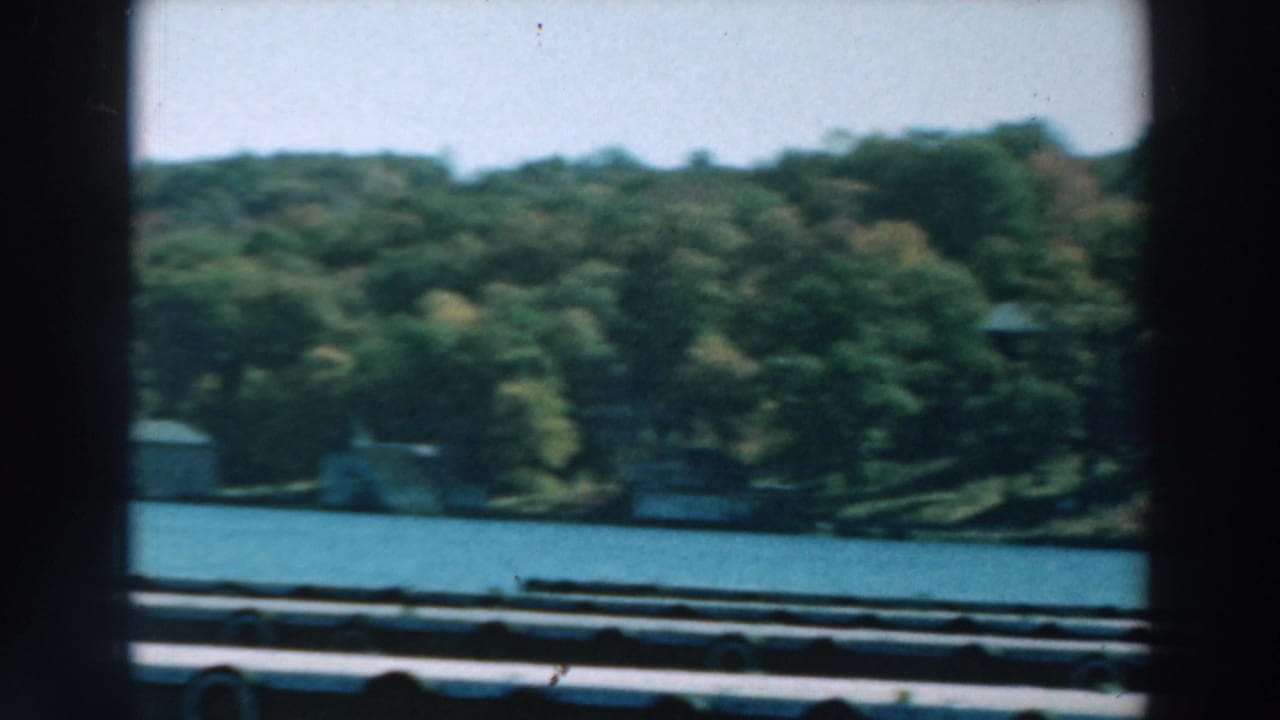 Blue lake seen from a boat with wooded shoreline and distant lakeside structures.