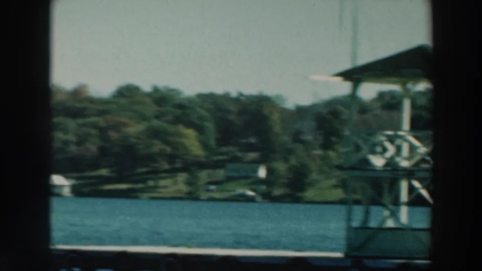 A small covered platform or watchtower stands near the wooded Lake Winnebago shore as seen from a moving boat.