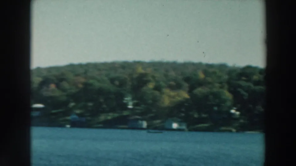 A soft 8mm view across Lake Winnebago shows blue water, dense trees, and scattered houses along the far shore.