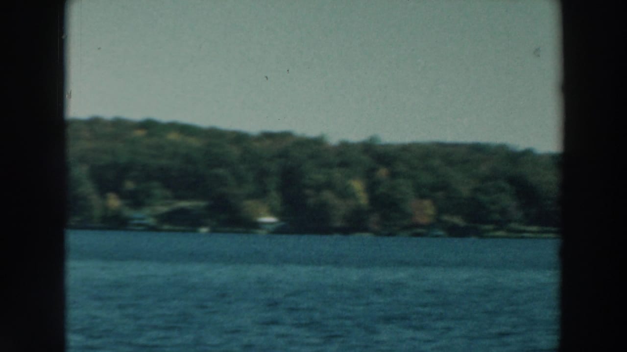 Lake Winnebago shoreline in 1964, seen across blue water with a central dark boat-window edge in the frame.