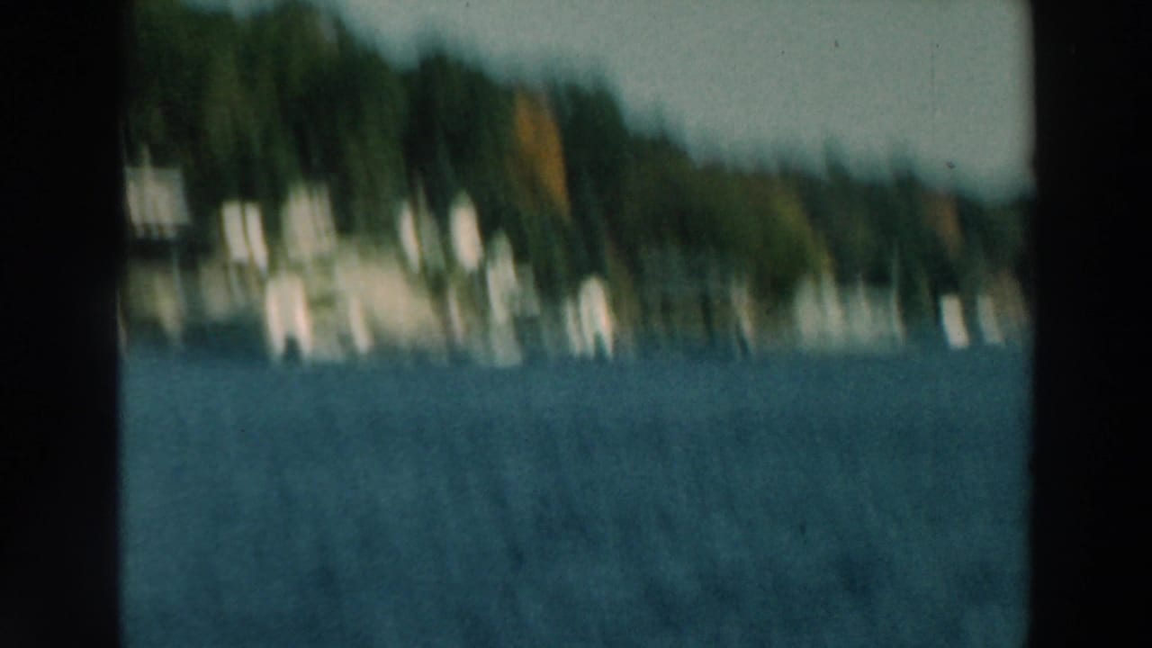 Blurred lake view with wooded shoreline and dark film-frame borders.