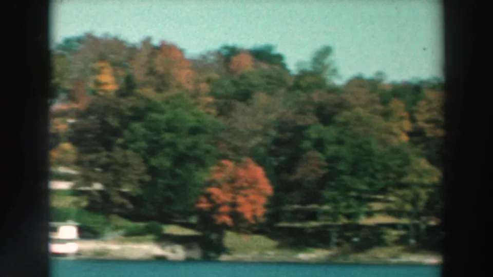 1964 8mm lakeside view on Lake Winnebago, with autumn foliage and small structures along the shore.