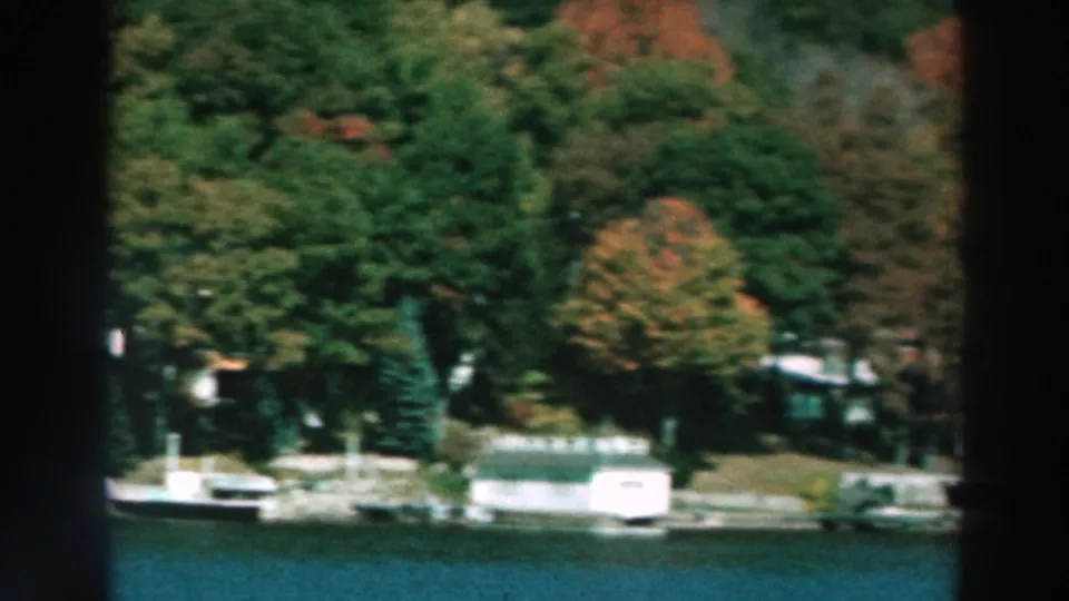 1964 Lake Winnebago shoreline with docks, small boats, trees in autumn color, and lake water in the foreground.