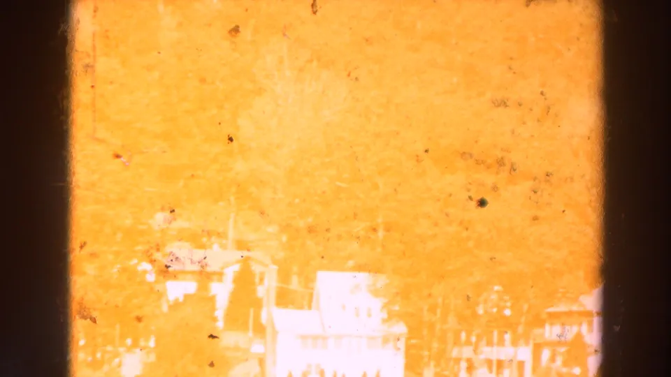 Overexposed 1964 Lake Winnebago home-movie frame with faint white houses, shoreline trees, and heavy warm color shift.