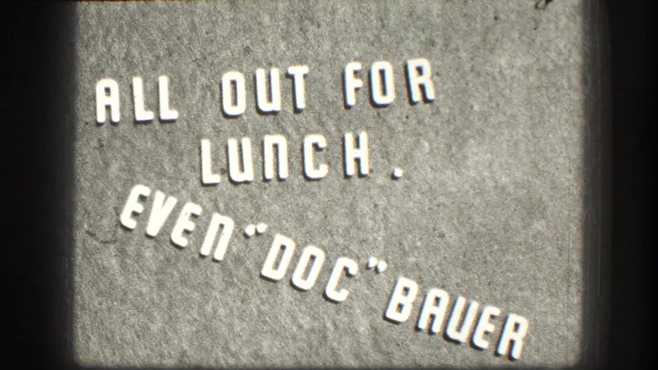 1958 Kansas home-movie title card with white raised letters reading ALL OUT FOR LUNCH. EVEN "DOC" BAUER.