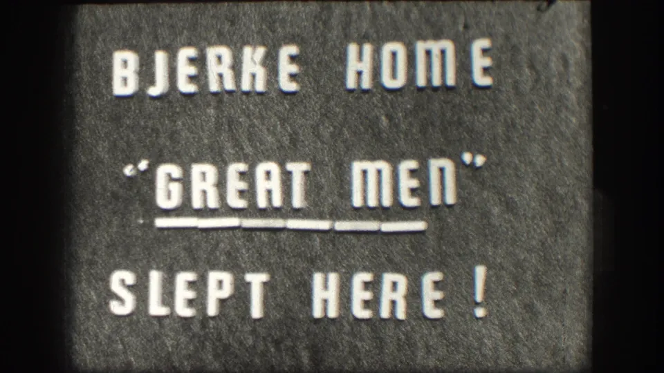 Cropped 8mm frame of the Bjerke Home plaque, showing the quoted Great Men line and Slept Here inscription.