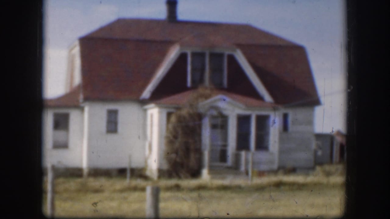 1958 Kansas 8mm frame showing a white rural house with a red roof, porch, open grass, and dark film gate edges.