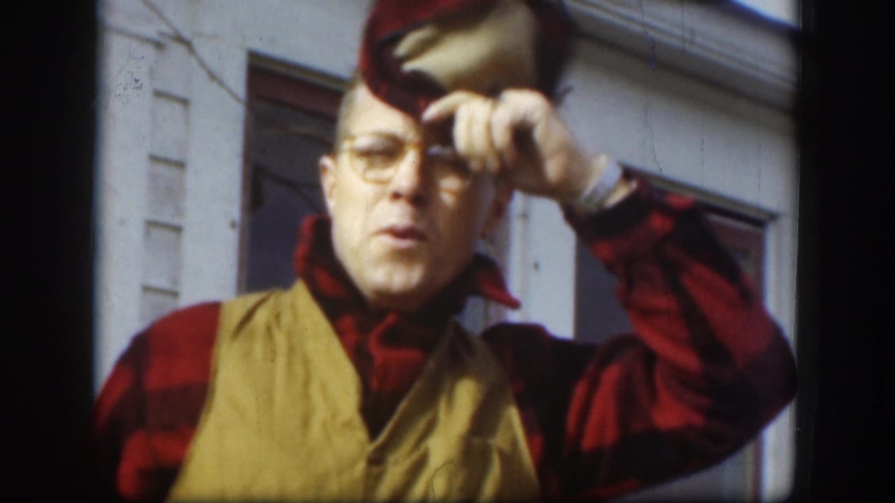 Adult man lifts the brim of his cap while facing the camera outdoors.