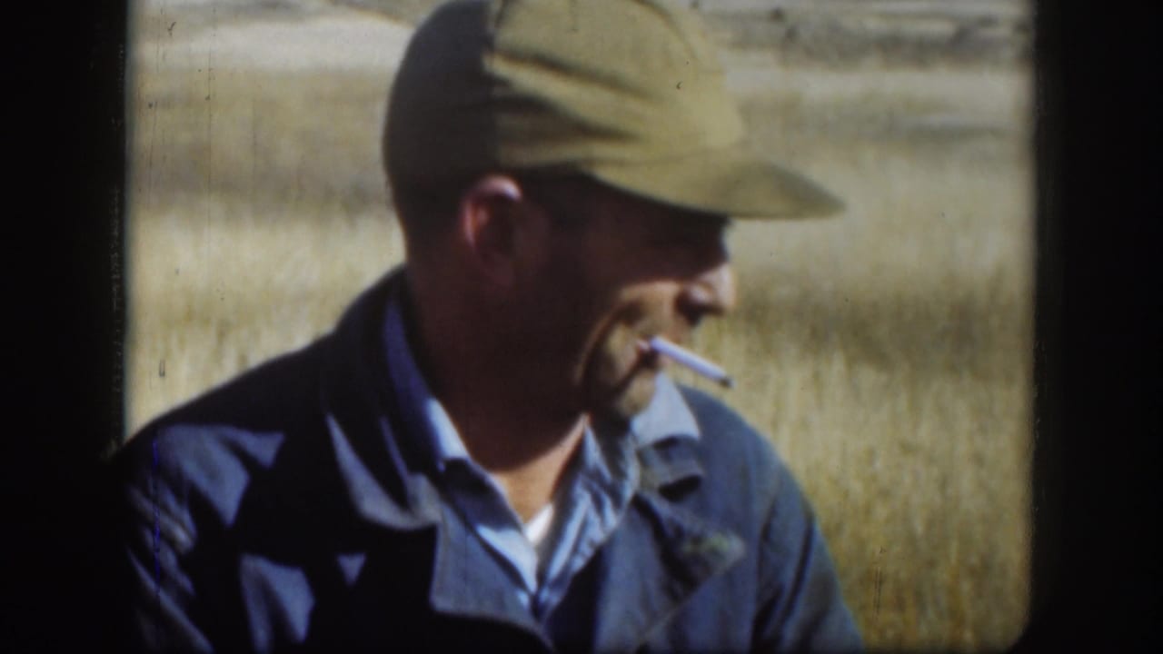 Adult man in a green cap smoking in a dry grass field.