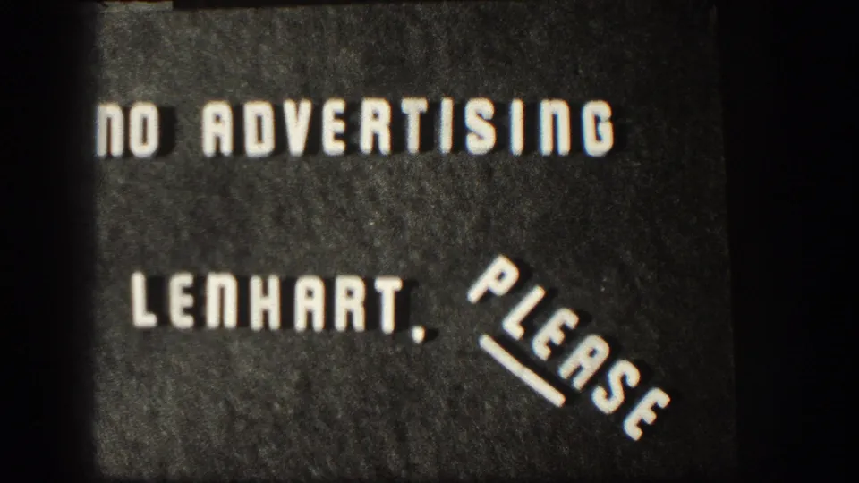 Spliced 8mm intertitle card with white lettering reading NO ADVERTISING LENHART, PLEASE against a dark textured background.