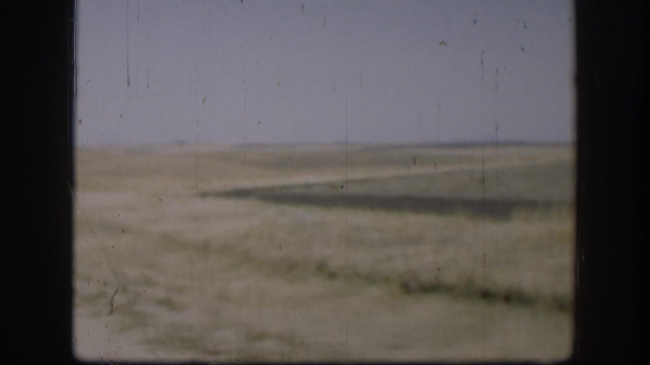 Kansas prairie view with a low horizon, pale sky, and sparse vegetation in 1958 8mm home-movie footage.