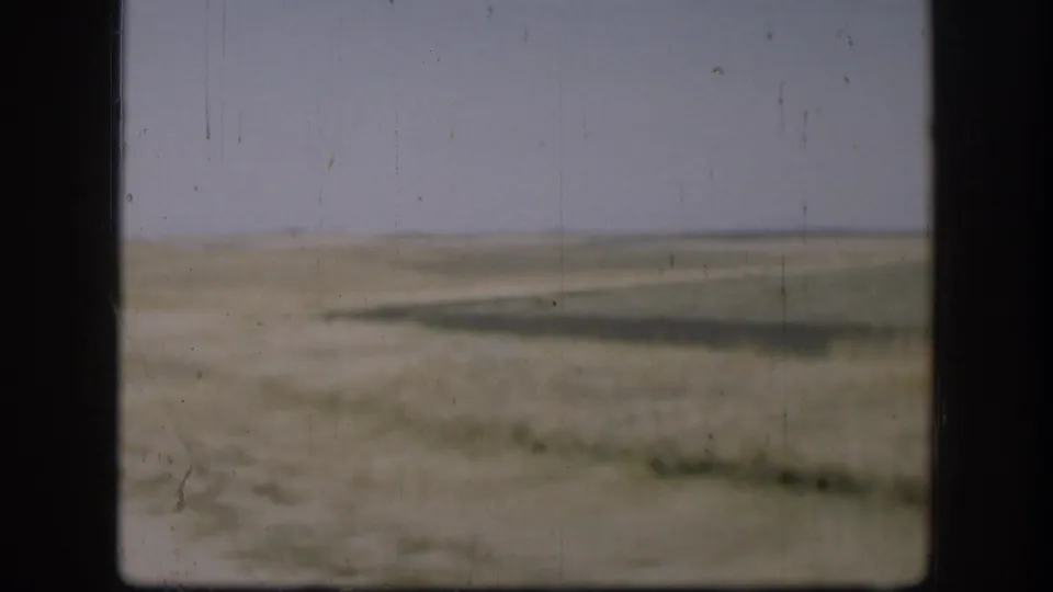 Kansas prairie view with a low horizon, pale sky, and sparse vegetation in 1958 8mm home-movie footage.