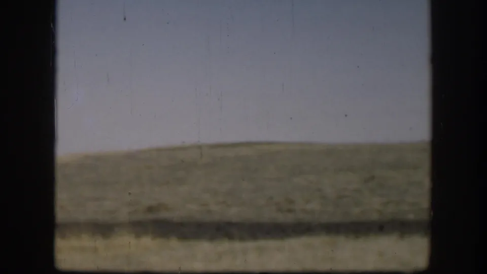 Kansas rural view from 1958 with green-brown hills, pale sky, and a heavy dark frame crossing the foreground.