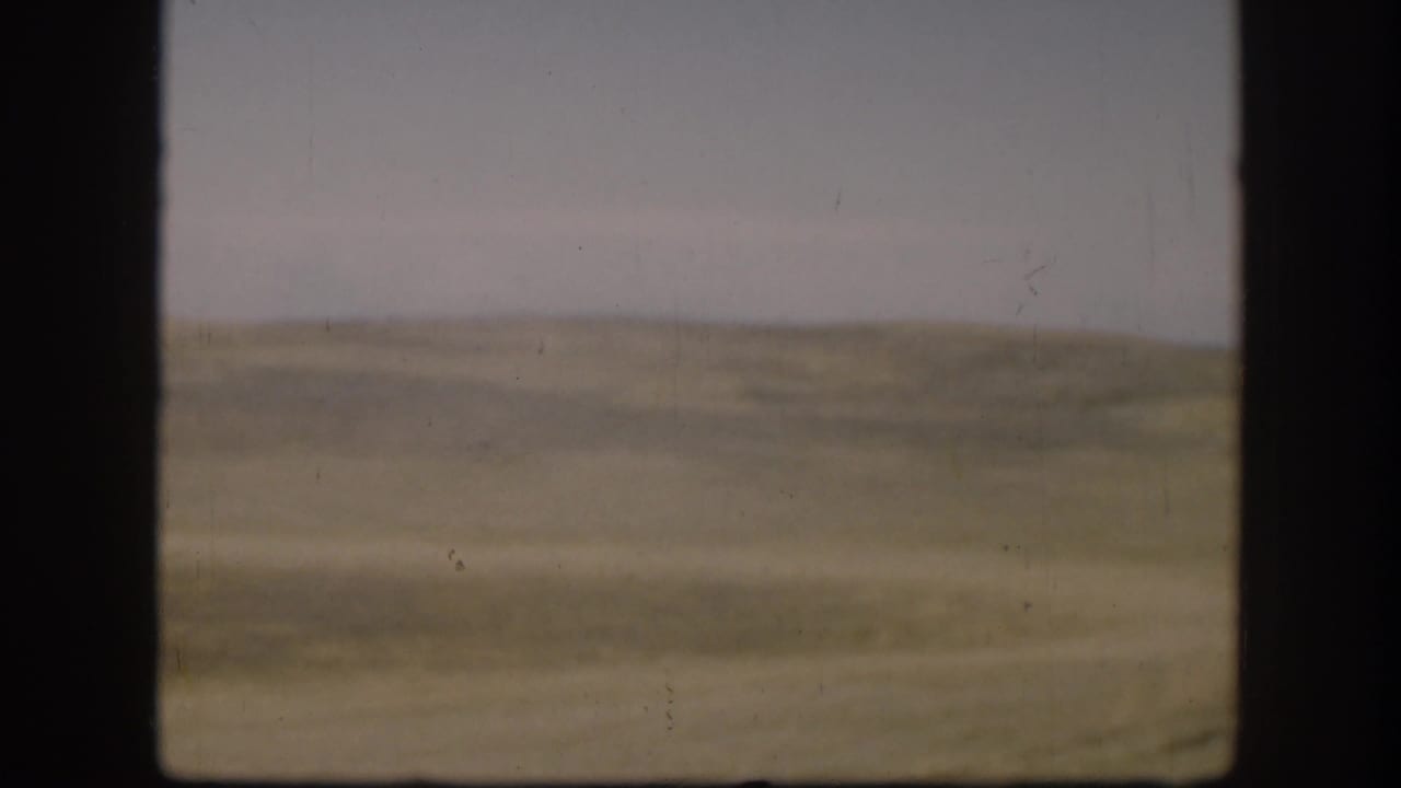 Soft 8mm view of open Kansas grassland in 1958, with a low horizon and faded color across the frame.