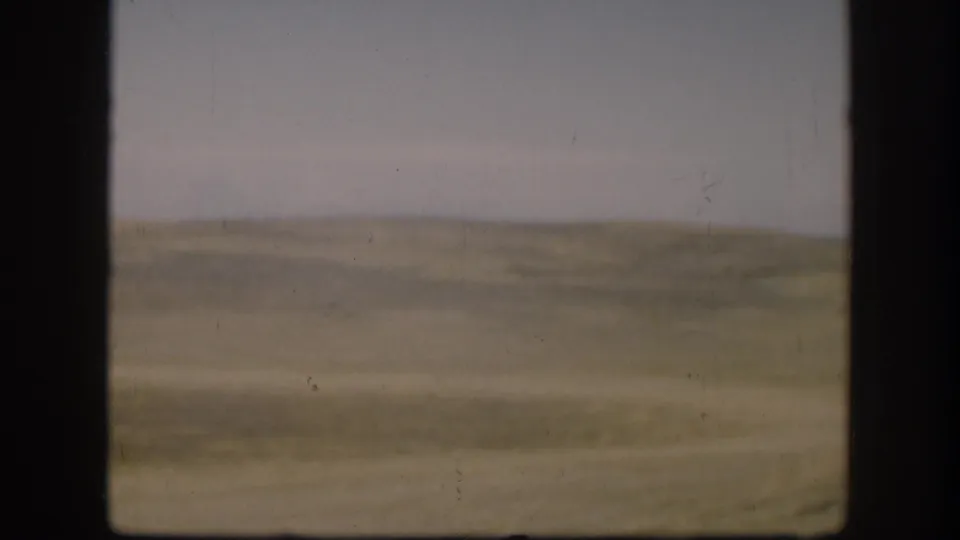 Soft 8mm view of open Kansas grassland in 1958, with a low horizon and faded color across the frame.