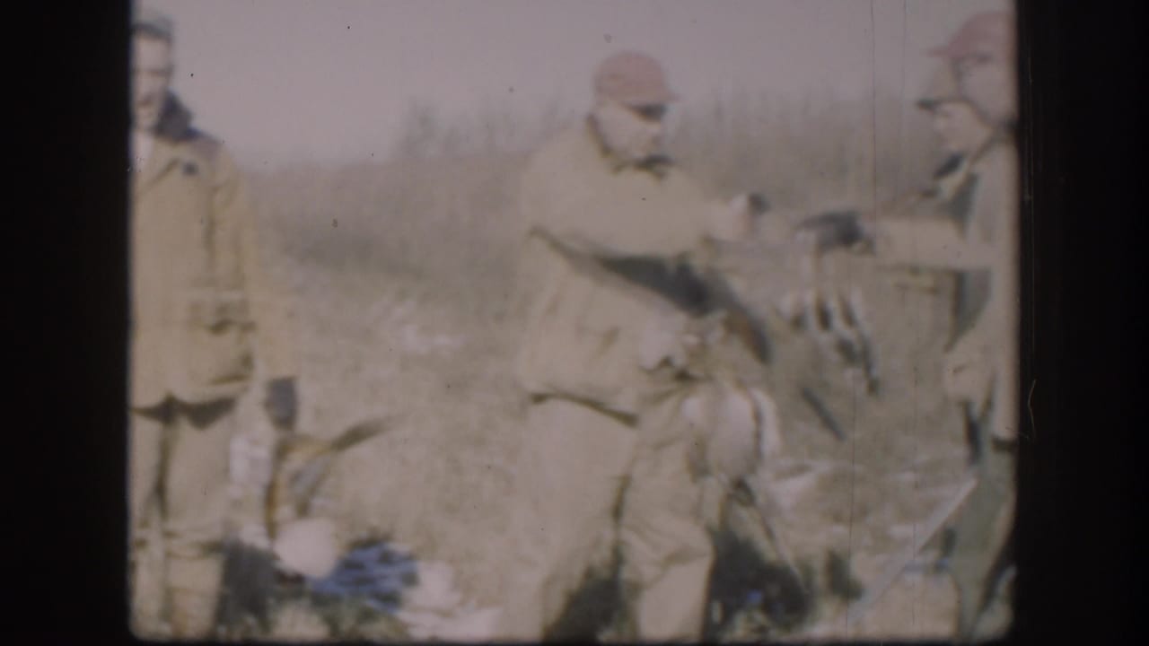 Adult hunters in Kansas appear to adjust or display game birds while holding shotguns in a faded 8mm frame.