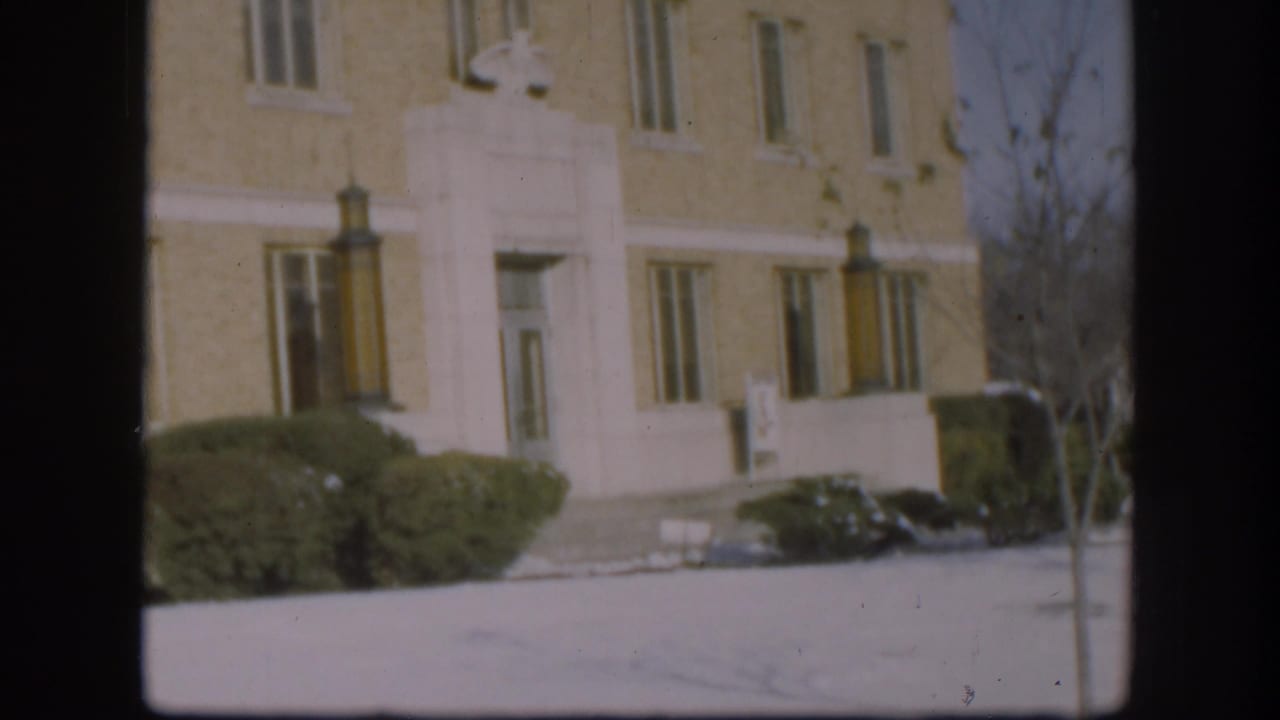 Brick courthouse entrance with white trim, shrubs, steps, snow-covered ground, and dark 8mm frame borders.