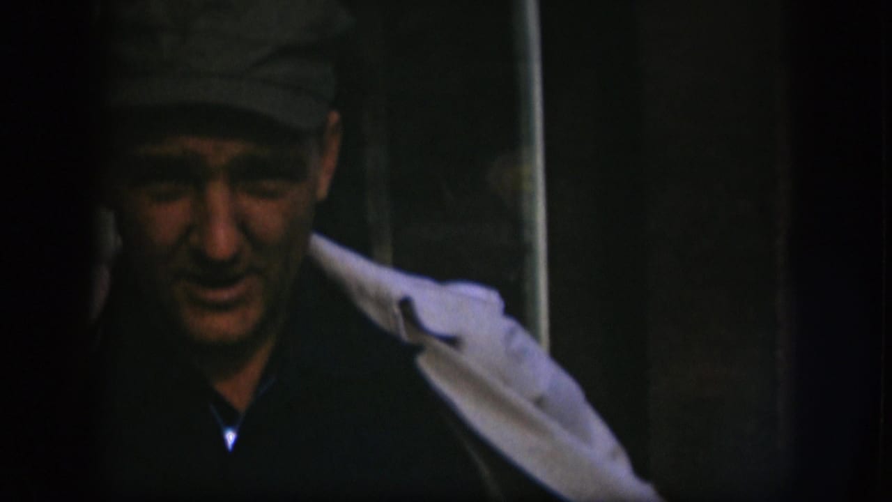 In this 1958 Kansas frame, the man appears lower in the shot, his cap, dark shirt, and light coat visible in dim light.
