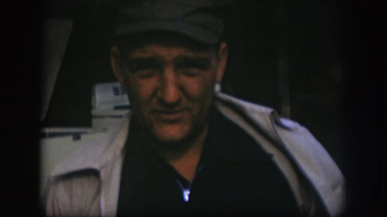 Close view of an adult man wearing a cap and light coat, filmed with soft 8mm grain in Kansas, 1958.