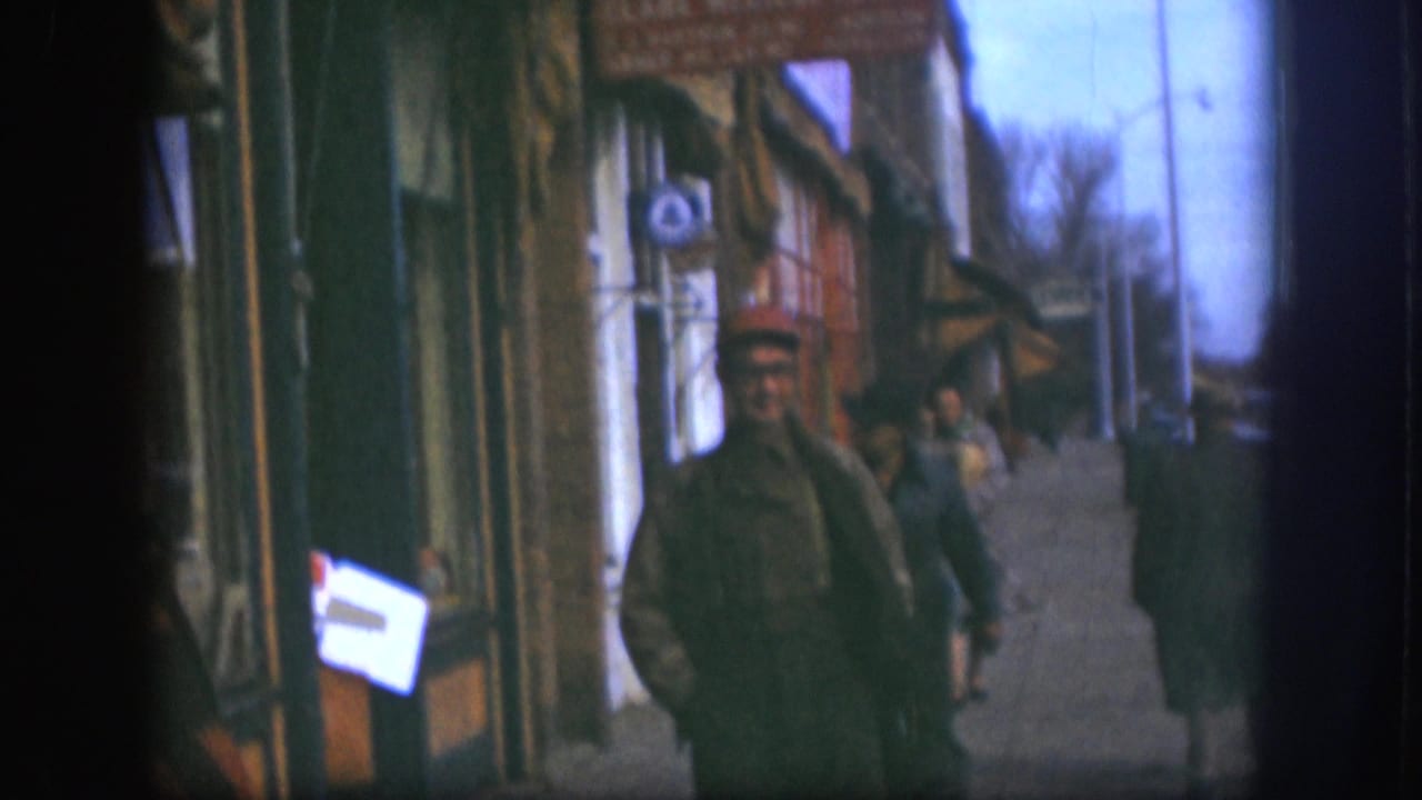 The 1958 Kansas street frame shows the original foreground subject mostly cropped out, with a red-capped pedestrian and storefronts down the sidewalk.