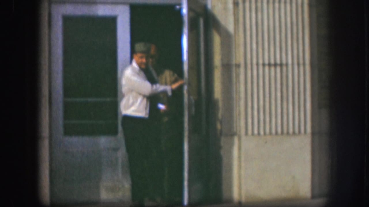 The 1958 Kansas clip shows a man in a light jacket leaning at a doorway, captured with grainy 8mm texture.