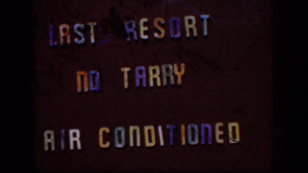 1958 8mm title-card frame with colored lettering on a dark background, partly cropped by the film gate.