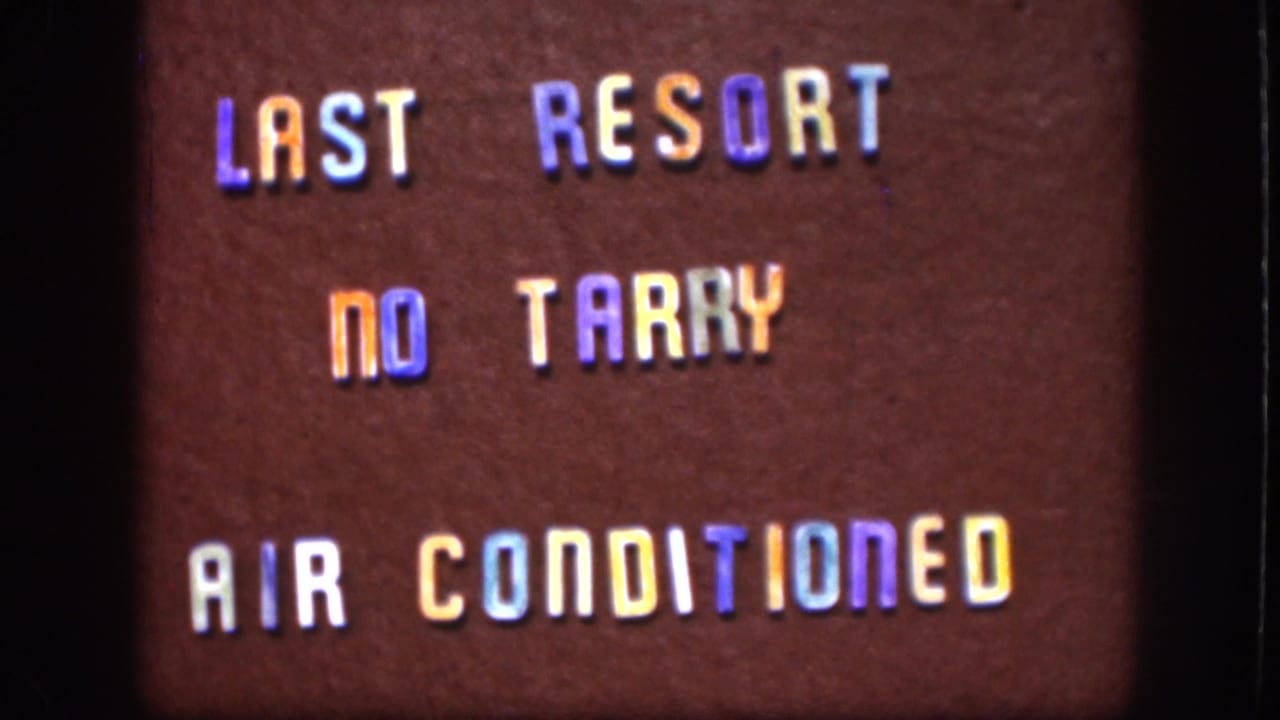 1958 Kansas 8mm frame showing the sign text shifted lower in frame, with warm color cast and visible home-movie grain.