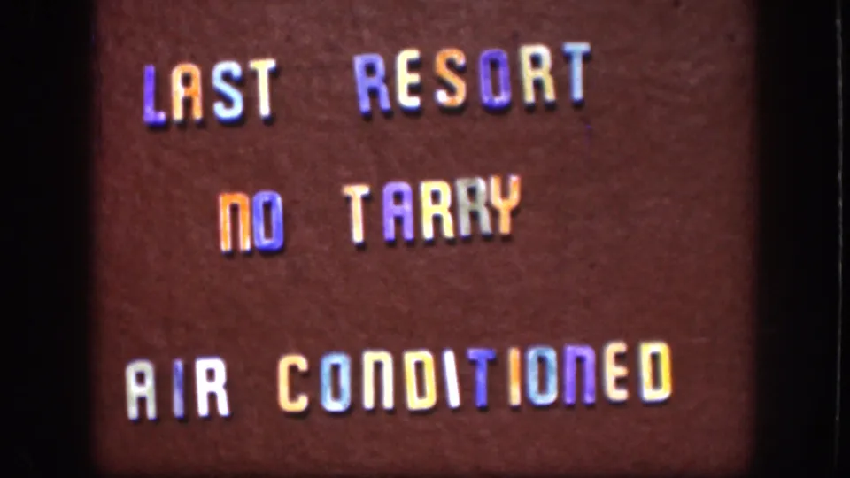 1958 Kansas 8mm frame showing the sign text shifted lower in frame, with warm color cast and visible home-movie grain.