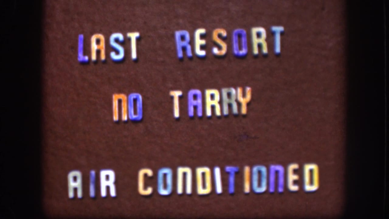 1958 Kansas 8mm frame of a brown sign with multicolored letters reading LAST RESORT NO TARRY AIR CONDITIONED.