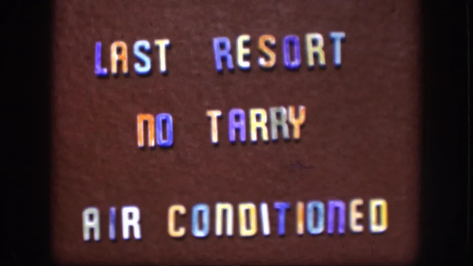 1958 Kansas 8mm frame of a brown sign with multicolored letters reading LAST RESORT NO TARRY AIR CONDITIONED.
