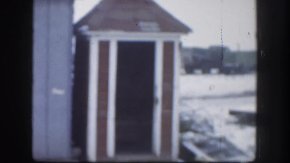 1958 Kansas 8mm frame of the same small gabled structure in snow, framed slightly off center with soft focus.