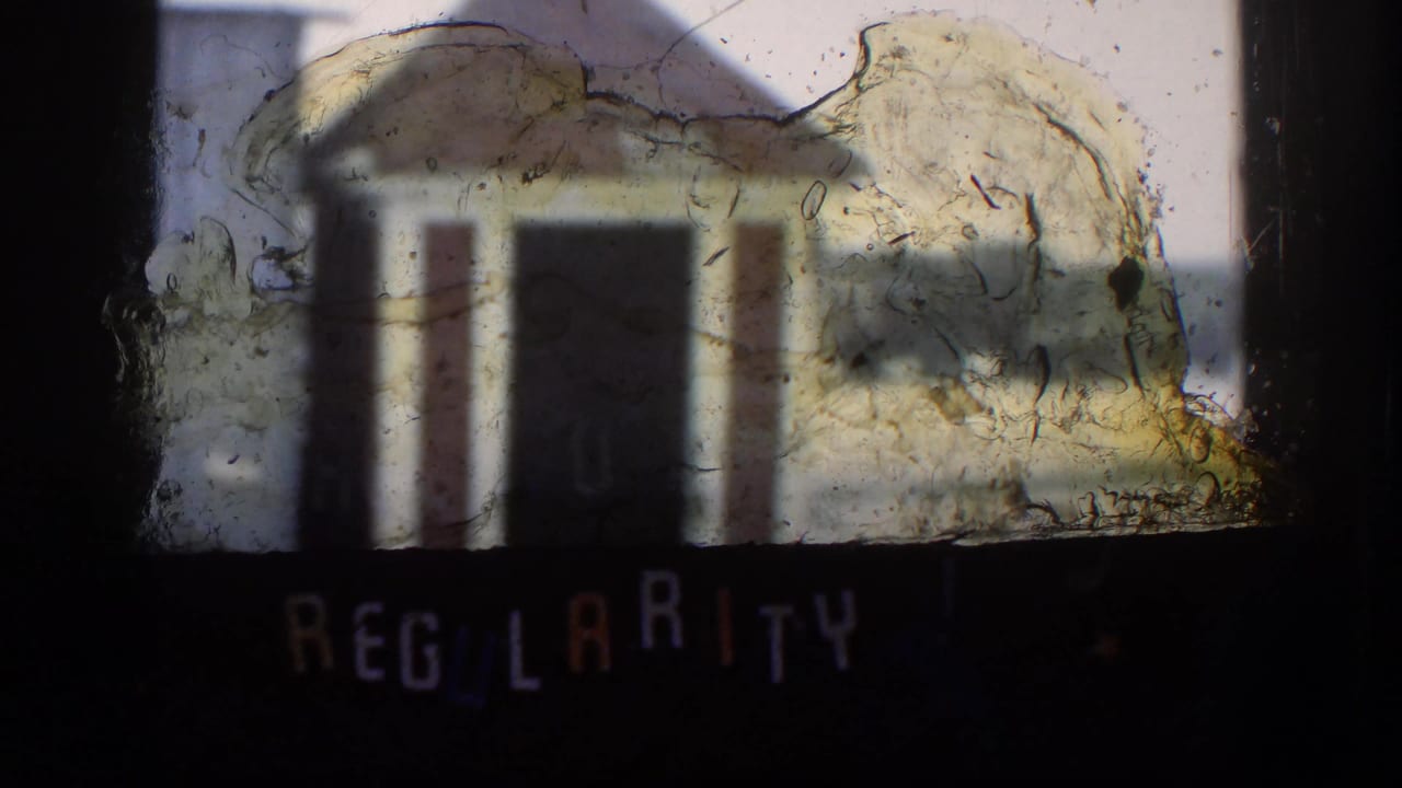 A damaged 8mm frame from the Kansas clip shows the shed obscured by film residue, with partial title lettering near the bottom.
