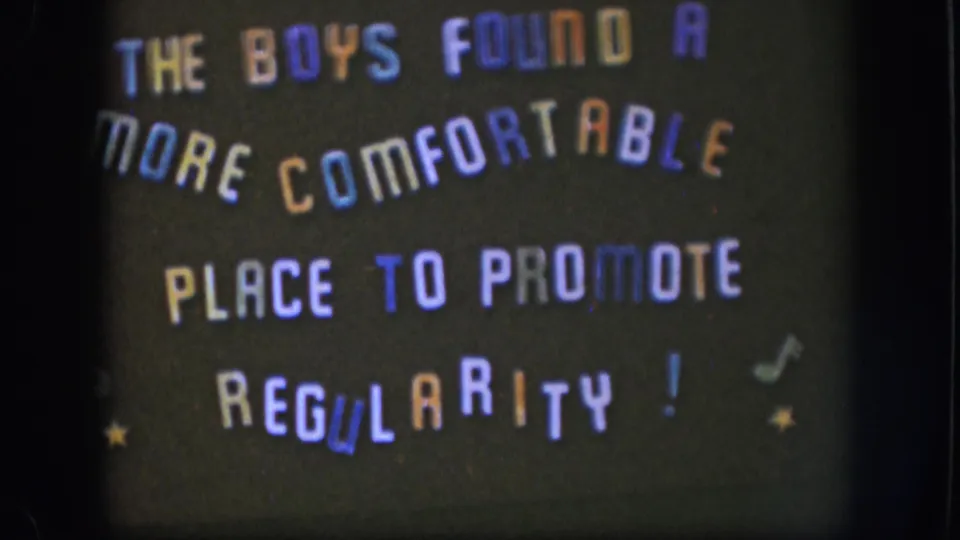 1958 Kansas 8mm frame showing a dark handmade title card with multicolored text, small stars, and musical-note marks.