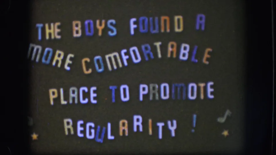 1958 Kansas home-movie frame of the same playful title card, with orange, blue, purple, and white letters on black.