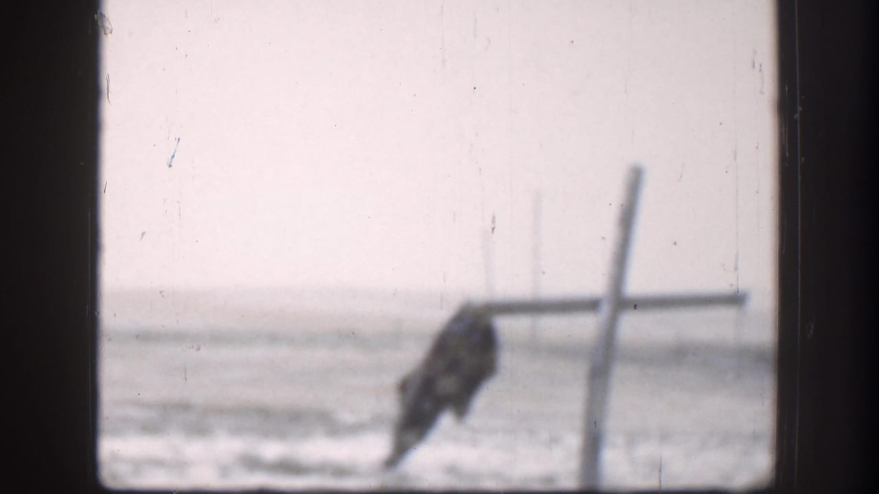 1958 Kansas 8mm frame showing a bird-like shape or object by a post with snow-covered ground in the background.