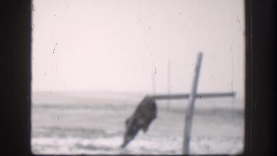 1958 Kansas 8mm frame showing a bird-like shape or object by a post with snow-covered ground in the background.
