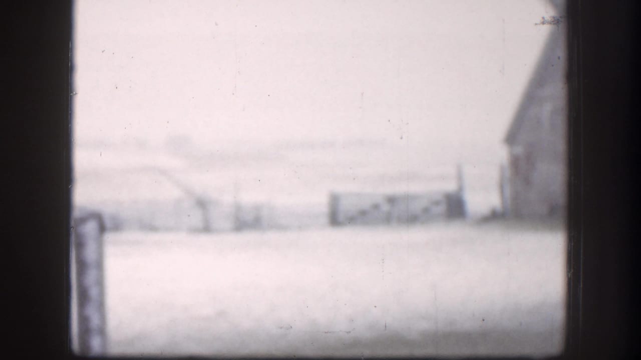 Snowy farm landscape seen through a dark window or door frame.