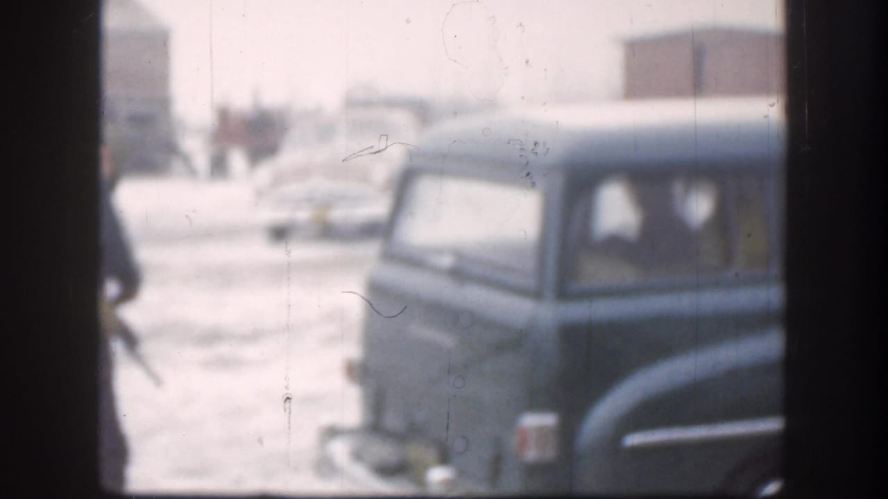 Snowy 1958 Kansas view of a dark mid-century automobile, partially obscured by window framing and winter haze.