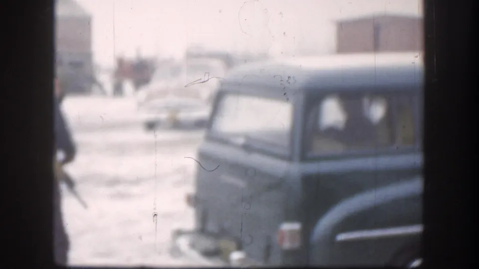 Snowy 1958 Kansas view of a dark mid-century automobile, partially obscured by window framing and winter haze.
