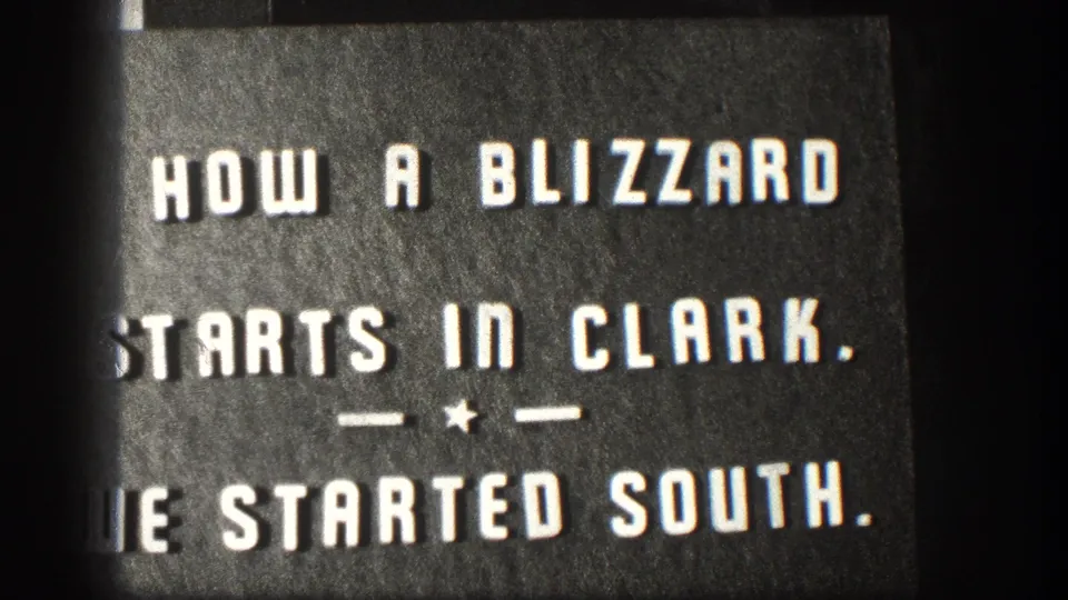 Black title card with white lettering describing the blizzard in Clark and the filmmakers starting south.